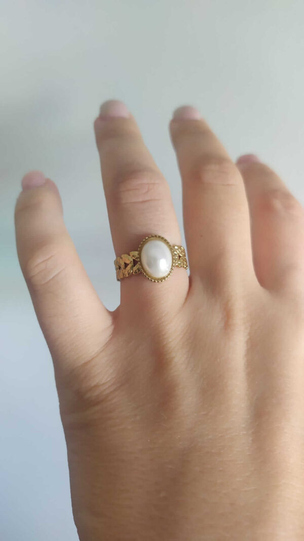 Anel ajustável em aço com pérola no centro e laterais com folhas trabalhadas, dourado