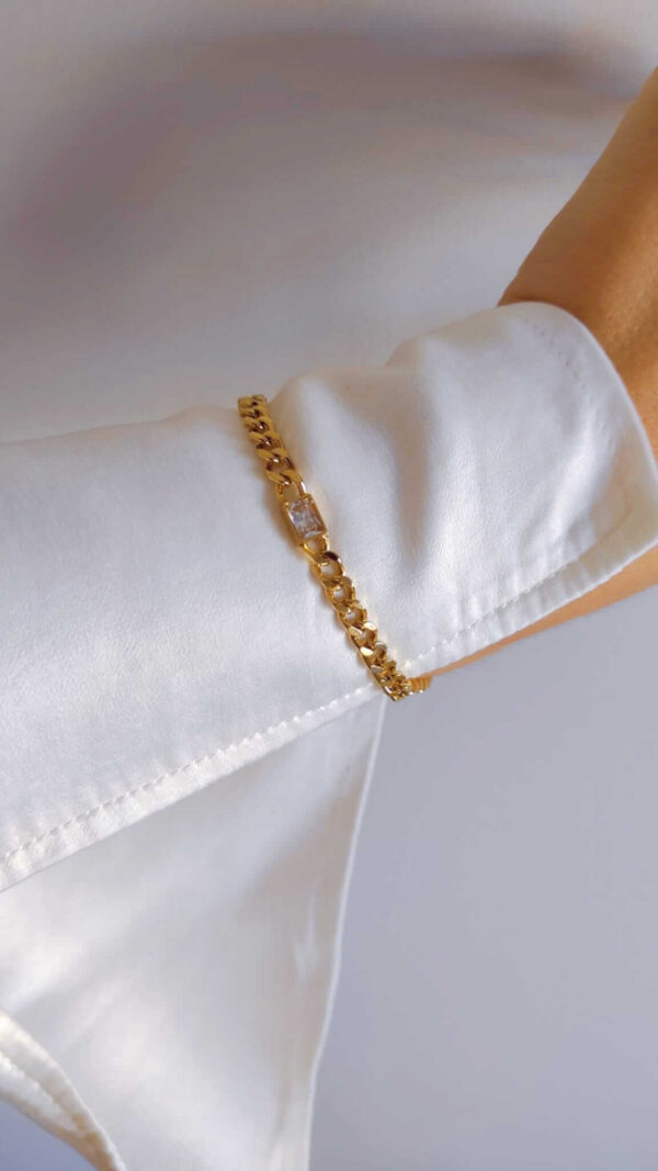 Pulseira em aço com fio de largura média e pendente retangular com brilhante em dourado