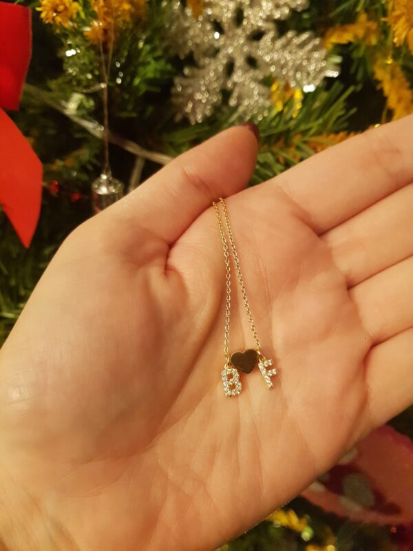 Colar com fio fino em aço e dois pendentes em forma de letra em cobre com zircónias, separados por um pendente em forma de coração