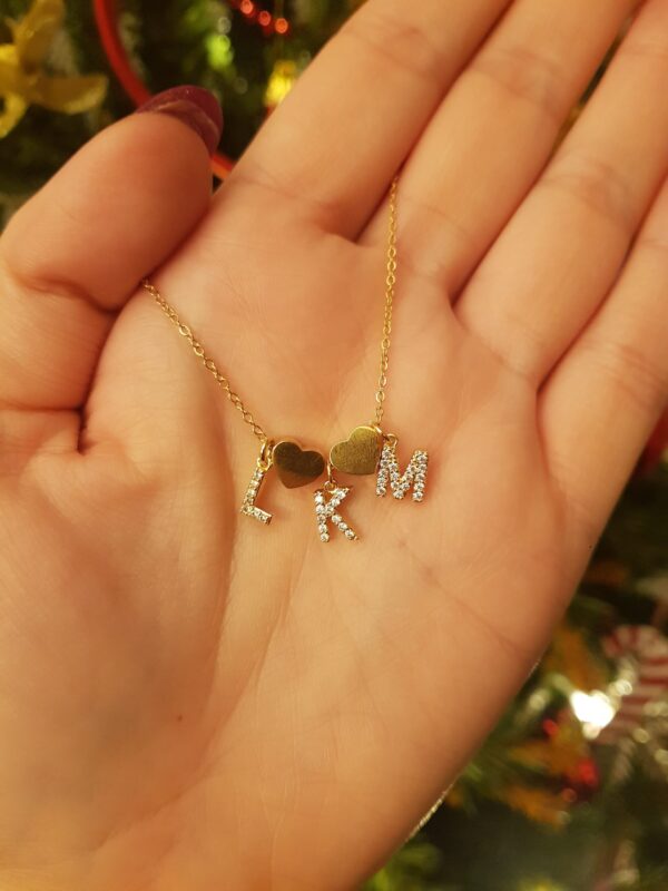 Colar com fio fino em aço e três pendentes em forma de letra em cobre com zircónias, separados por um pendente em forma de coração