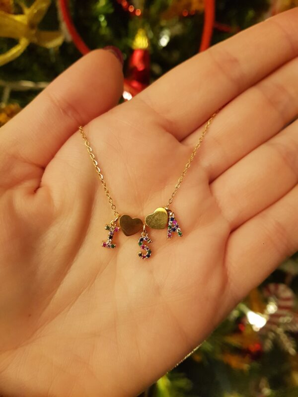 Colar com fio fino em aço e três pendentes em forma de letra em cobre com zircónias, separados por um pendente em forma de coração