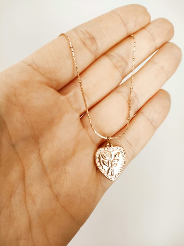 Colar em aço com fio fino trabalhado e pendente em forma de coração com flor gravada