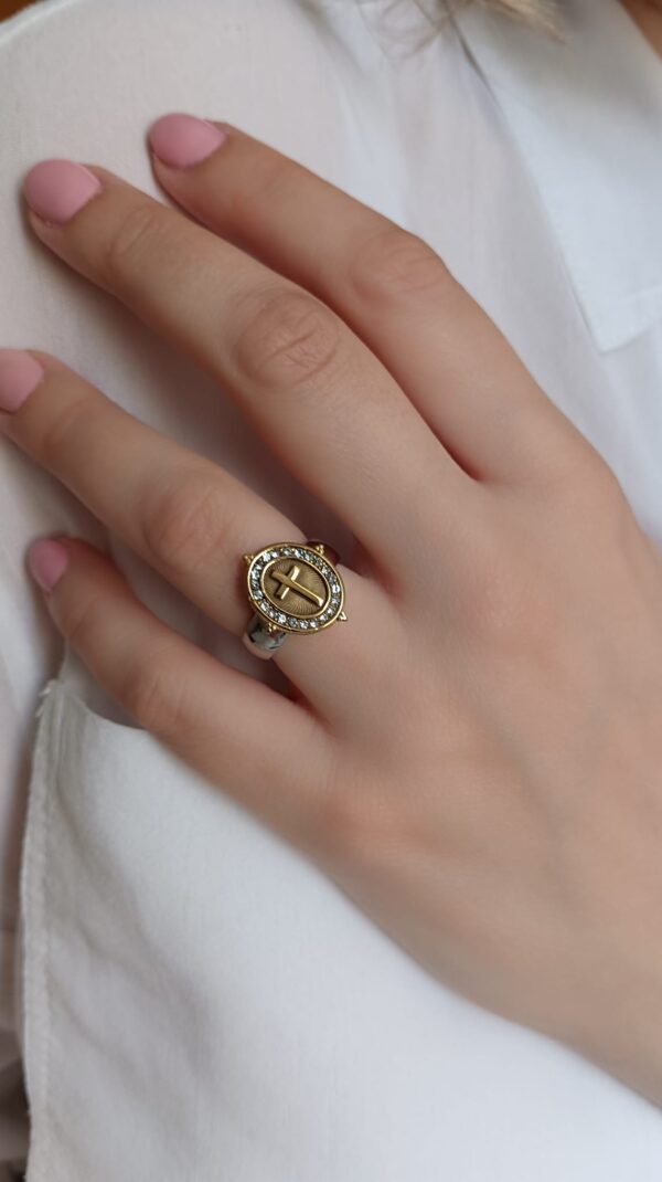 Anel em aço prateado e dourado, oval com cruz e brilhantes ao centro