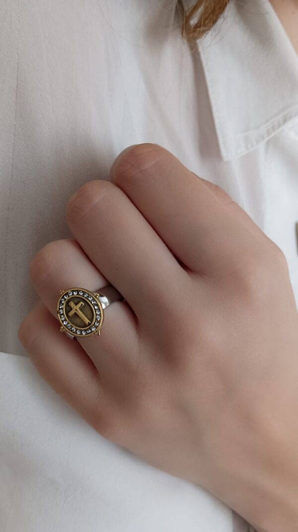 Anel em aço prateado e dourado, oval com cruz e brilhantes ao centro