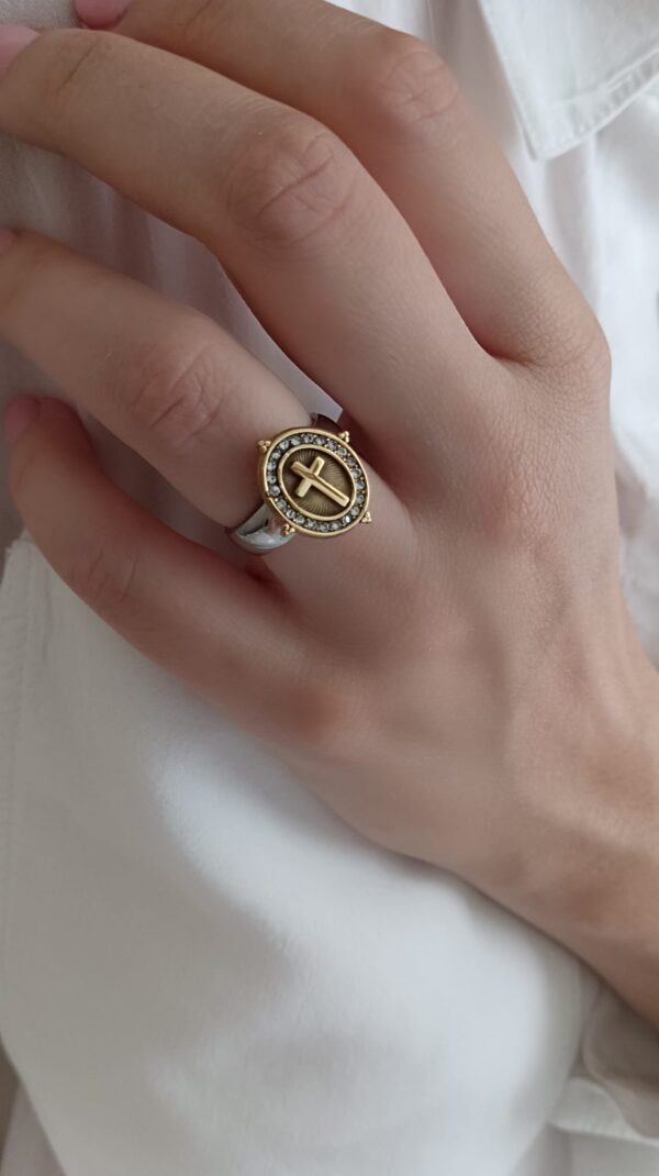 Anel em aço prateado e dourado, oval com cruz e brilhantes ao centro