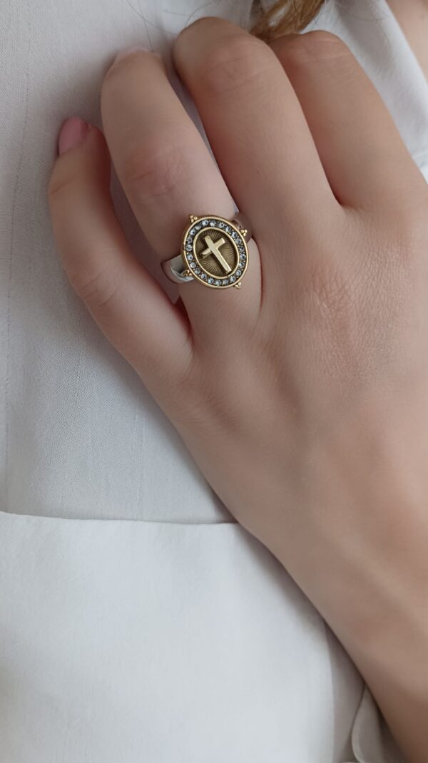 Anel em aço prateado e dourado, oval com cruz e brilhantes ao centro